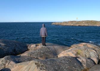 A person standing on rocks near sea shore.
