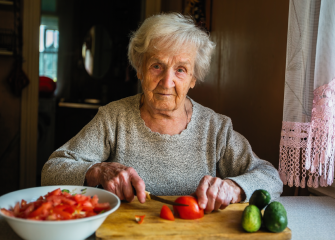 Vanhempi nainen laittaa ruokaa.