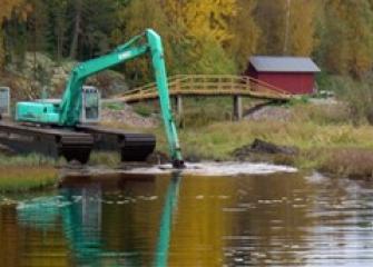 Grävmaskin muddrar flodstranden.