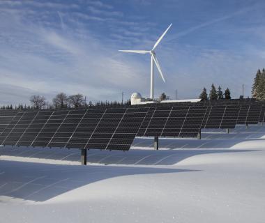 Aurinkopaneeleja ja tuulimylly talvisessa maisemassa.