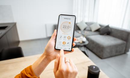 The temperature in the living room is adjusted using a mobile phone.