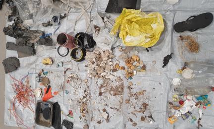 Pressulle asetettuja rannalta löytyneitä roskia kuten eri väristä muovia, alumiinia, sandaali sekä köysiä. 