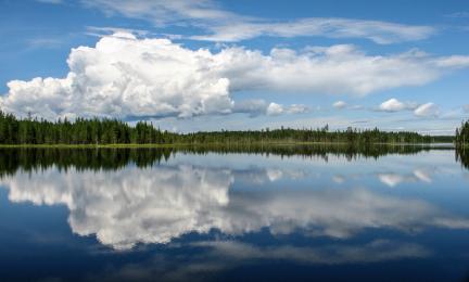 Tyyni järvi, jonka pinnasta heijastuu taivaalla oleva pilvi.