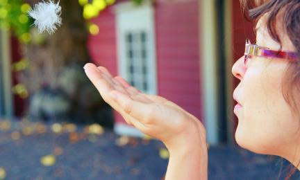 Tyttö puhaltaa höyhentä