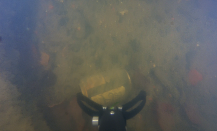 Robottikamera keräämässä tölkkiä sameassa vedessä. 