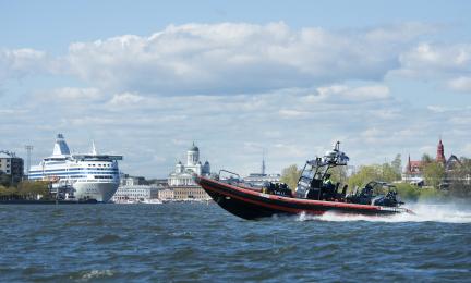 Kovaa ajava moottorivene ja taustalla iso laiva.