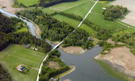 Ilmasta kuvattu joki, jonka ympärillä on peltoja ja taloja.