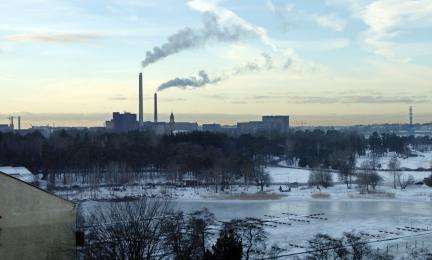 Talvinen maisema ja voimala, jonka piipusta tupruttaa savua. 