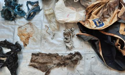 Merestä kalastettuja roskia, kuten eriväristä muovia, alumiinia ja kangasta aseteltuna pressun päälle.